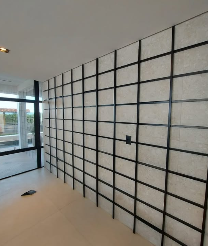 Revestimento de parede em grade metálica preta sobre porcelanato