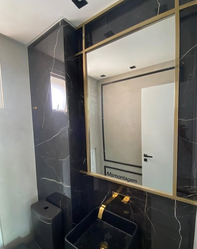 Moldura de espelho em aço dourado em lavabo de mármore